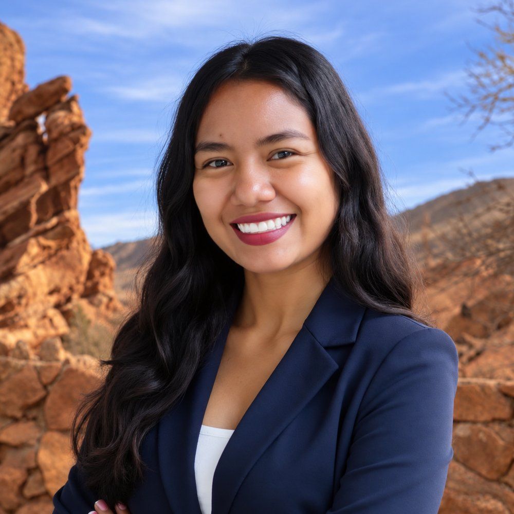 Yaquelin Rivera in navy blazer smiling outdoors with rocky landscape background.