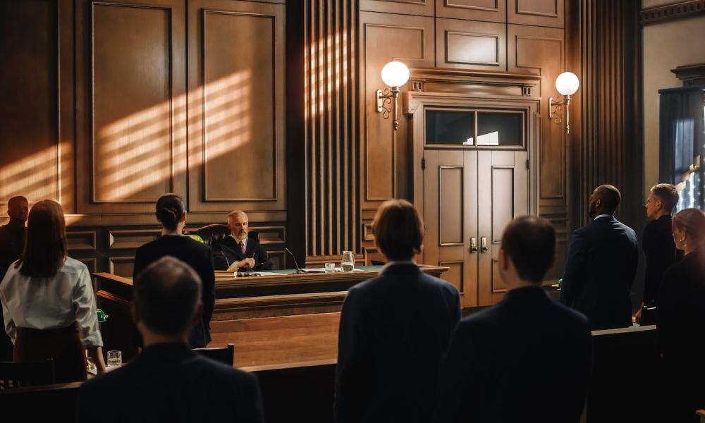 Professional courtroom scene with judge presiding and people standing in attendance, captured in warm lighting.