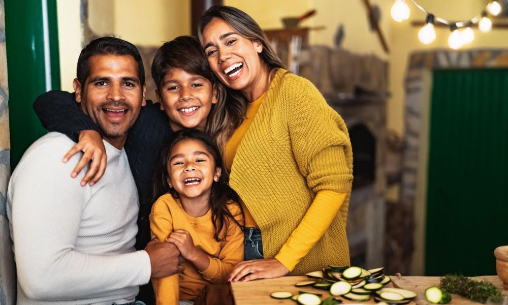 Happy family in cozy kitchen, smiling while preparing fresh vegetables.