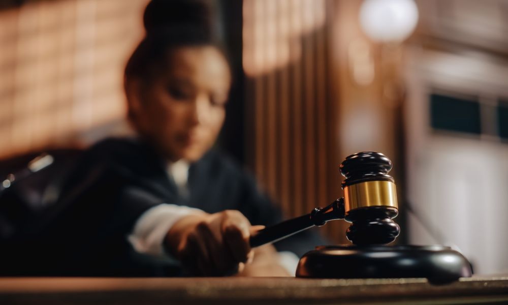 Judge striking gavel in court, signifying a legal decision or verdict in a courtroom setting.