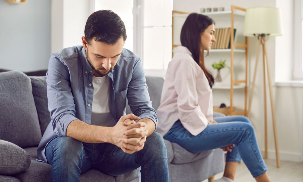 Couple sitting apart on a sofa, expressing tension and conflict in a relationship.