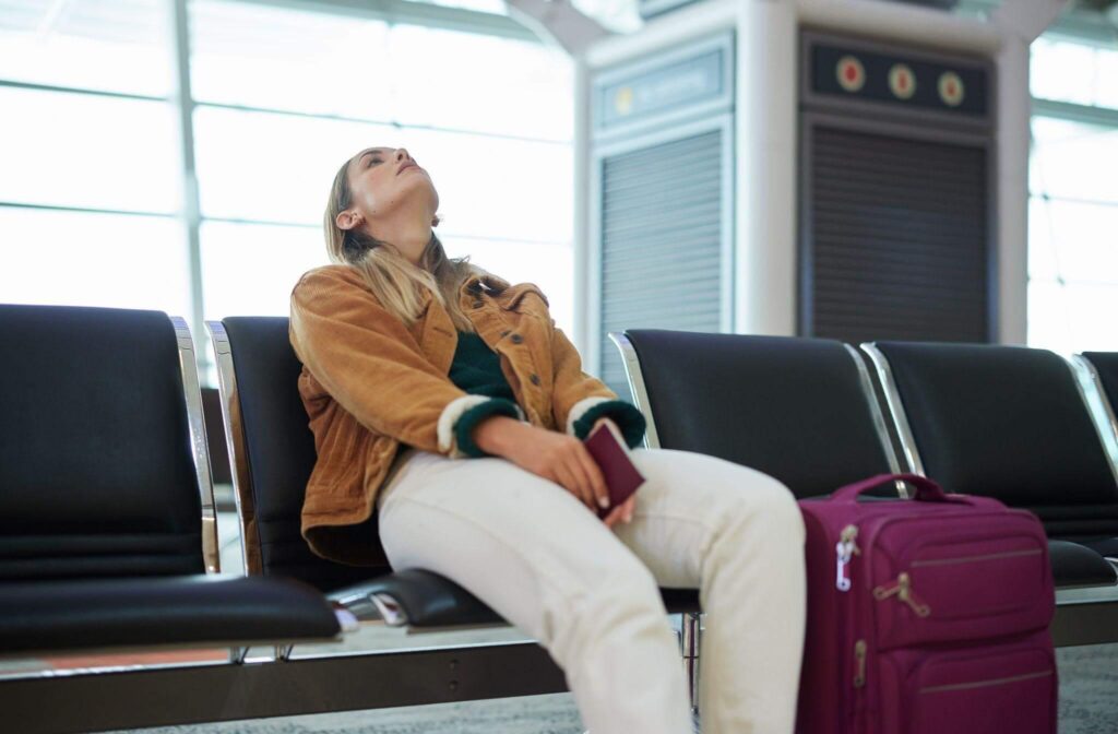 a woman sitting on a bench next to a purple suitcase